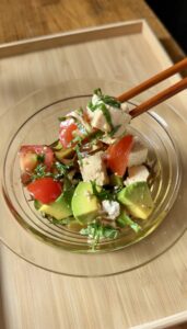 Japanese tofu and avocado salad with cherry tomatoes, shiso, and shio kombu in a glass bowl