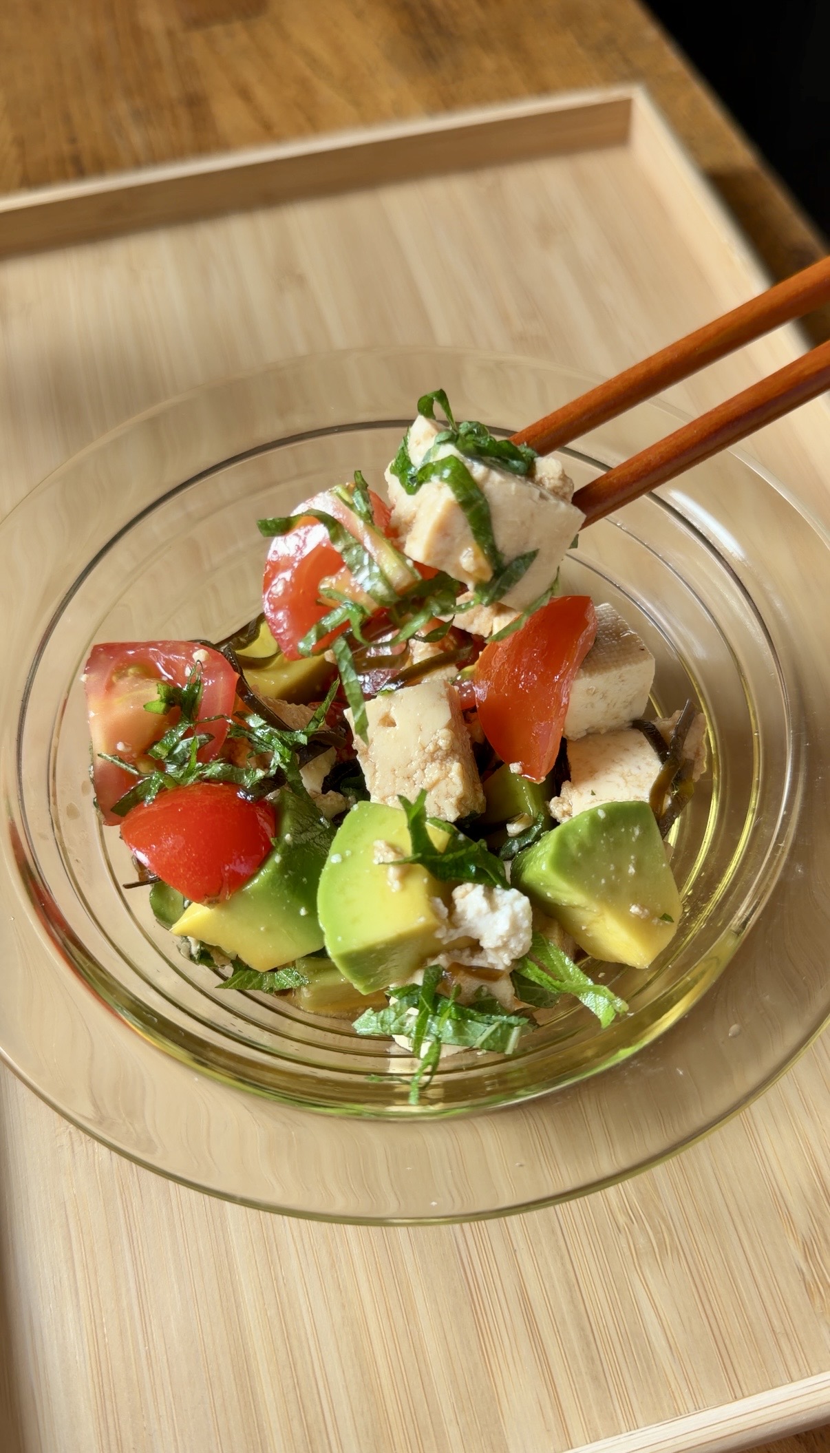 Japanese tofu and avocado salad with cherry tomatoes, shiso, and shio kombu in a glass bowl